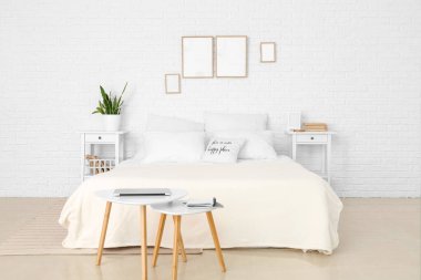 Boş çerçeve ve masalarla aydınlık yatak odasının içi