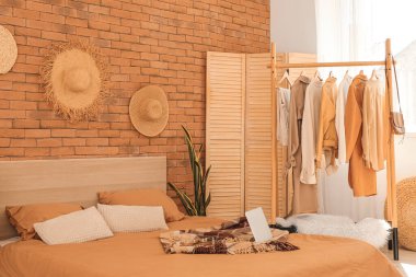 Askısı ve kıyafetleri olan şık bir yatak odası.