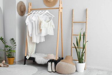 Raflı, elbiseli ve merdivenli hafif soyunma odasının içi.