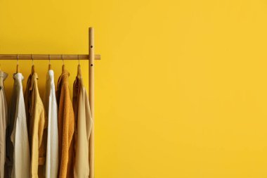 Sarı duvarın yanında modaya uygun kıyafetlerle dizilin.