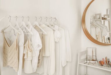 Soyunma odasındaki ışıklı duvarın yanında giysilerle dizilin.