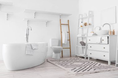 Modern banyo küveti, lavabosu ve banyo aksesuarları olan şık bir banyo.