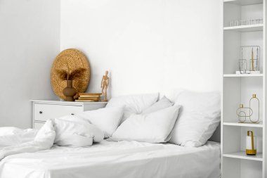 Beyaz duvarın yanında yumuşak çarşafları olan rahat bir yatak.