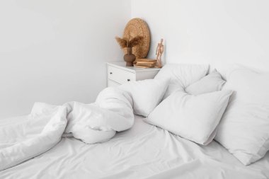 Beyaz duvarın yanında yumuşak çarşafları olan rahat bir yatak.