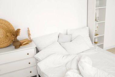 Yatak odasındaki beyaz duvarın yanında yumuşak çarşaflı yatak