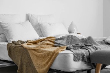 Beyaz yastıklı rahat bir yatak ve ışık duvarının yanında battaniye.