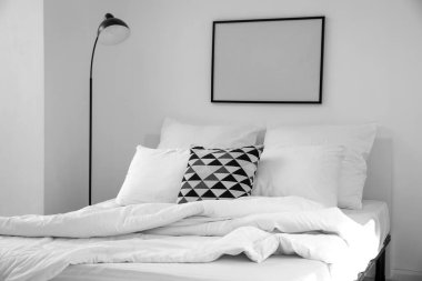 Yastıklı rahat bir yatak, lamba ve ışık duvarında boş bir çerçeve