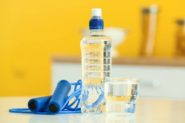 Mutfaktaki masada bir şişe su, cam ve ip atlama.