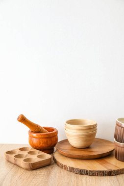 Mutfak gereçleri ahşap masada, ışık duvarının yanında.