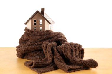 Beyaz arka planda sarı masa üzerinde eşarplı ev modeli. Isıtma kavramı