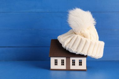 Mavi ahşap arka planda şapkası olan ev modeli. Isıtma kavramı