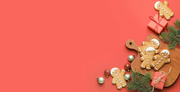 Tasty gingerbread cookies, gifts and Christmas decor on red background with space for text