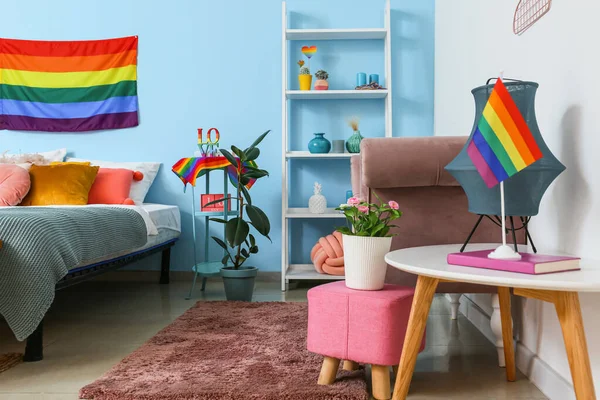 Güzel bitkiler, raf ünitesi ve masa üzerinde gökkuşağı bayrağı olan modern lamba.