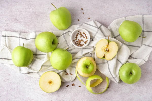 Fresh green apples and seeds on light background