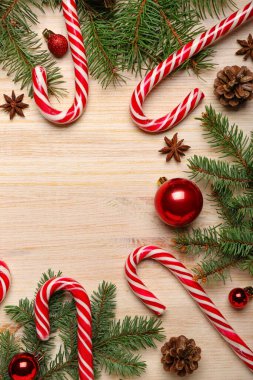 Lezzetli baston şekerleri, köknar dalları ve ahşap arka planda Noel topları olan kompozisyon