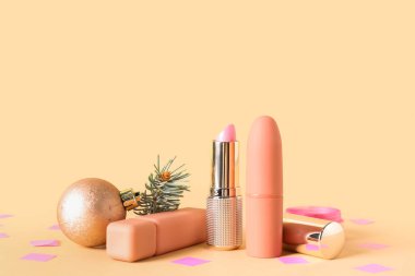 Dekoratif kozmetik seti, konfeti ve renkli arka planda Noel topu