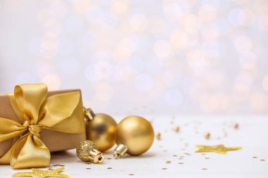 Bulanık ışıklara karşı masada hediyeli altın Noel baloları