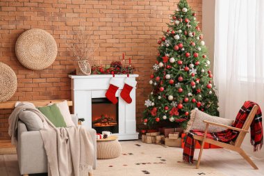Oturma odasının içinde şömine, kanepe ve Noel ağacı var.