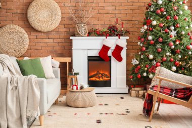 Oturma odasının içinde şömine, kanepe ve Noel ağacı var.
