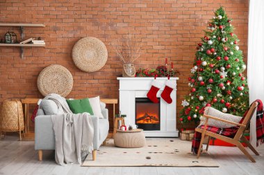 Oturma odasının içinde şömine, kanepe ve Noel ağacı var.