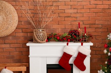 Ağaç dalları, mumlar ve şöminenin yanında Noel süsü olan bir vazo.