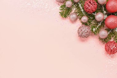 Güzel Noel baloları, köknar dalları ve pembe arka planda kar olan kompozisyon