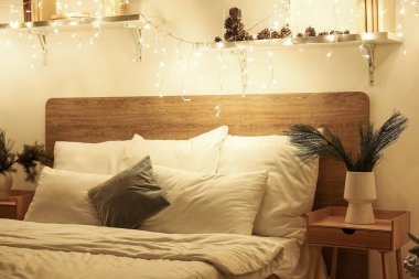 Yatak odasının içinde vazolarda Noel dalları ve geceleri parlayan ışıklar var.