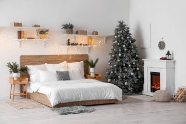 Yatak odasının içinde Noel ağacı, şömine ve parlayan ışıklar var.