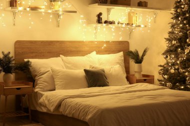 Yatak odasının içinde vazolarda Noel dalları ve geceleri parlayan ışıklar var.