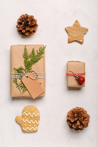 Composition with Christmas gifts, cookies and cones on light background