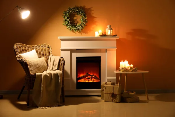 Interior of dark living room with Christmas wreath, fireplace and armchair