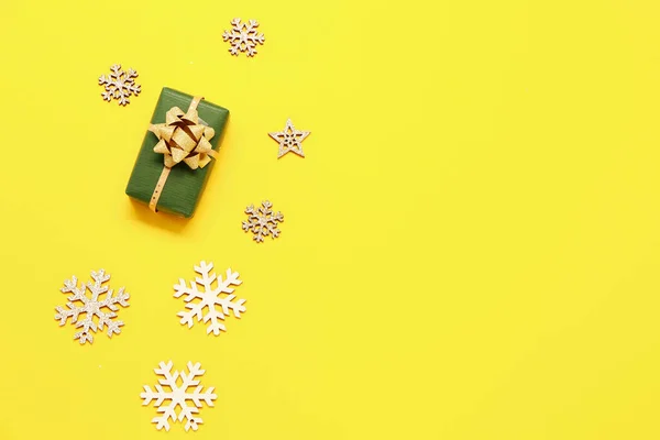 Composition with Christmas gift and decorations on yellow background