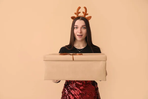 Surprised Young Woman Reindeer Horns Christmas Gift Beige Background — Stock Photo, Image