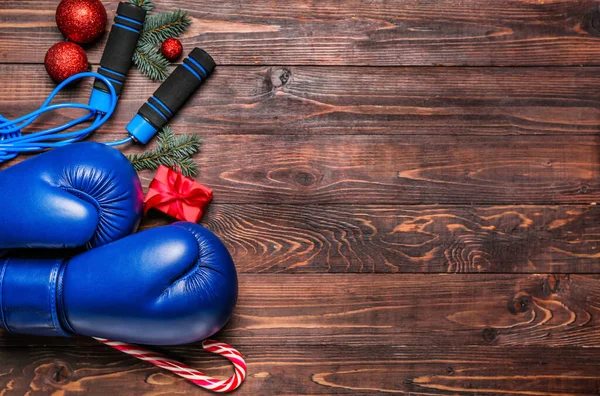 Boxing gloves with skipping rope, Christmas decor and gift on wooden background