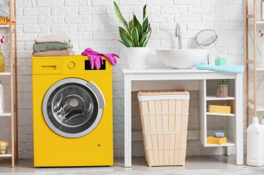 Banyonun içindeki parlak sarı çamaşır makinesi.