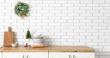 Noel ökseotu çelengi mutfaktaki beyaz tuğla duvarda asılı.