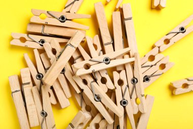 Sarı arka planda ahşap mandallar yığını, yakın plan.