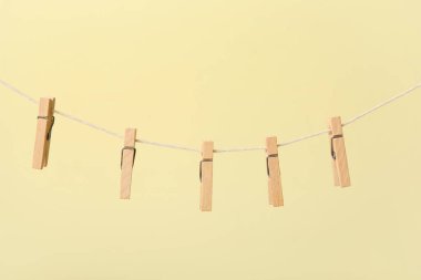 Ahşap mandallar renk arkaplanına karşı ipte asılı.