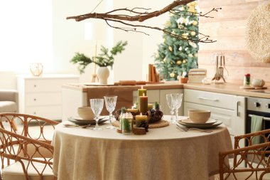 Noel sofrasında yanan mumlar ve mutfakta çelenkler.