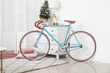Oturma odasında Noel ağacı ve lamba olan çekmecelerin yanındaki bisiklet.
