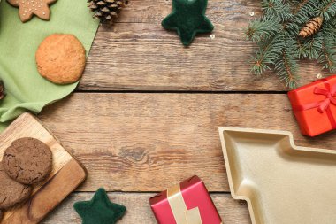 Noel dekorundan yapılmış çerçeve, kurabiyeler, tabak ve ahşap arka planda hediyeler