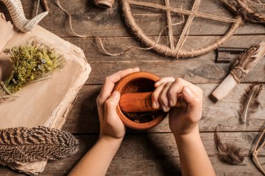 Genç cadı ahşap masada ayin yapıyor.