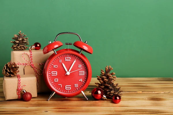 緑の壁の近くのテーブルの上にクリスマスボール ギフトやモミのコーンとヴィンテージ目覚まし時計 — ストック写真