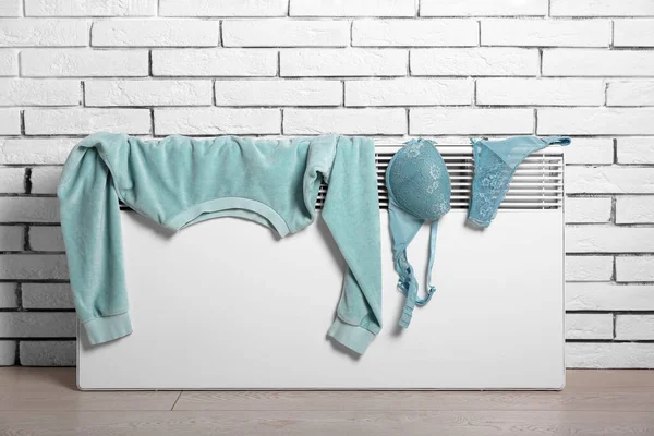 Kvinnlig Tröja Och Underkläder Torkning Elektrisk Radiator Nära Vit Tegelvägg — Stockfoto