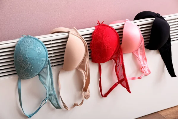 粉红墙壁附近电散热器上的女性胸罩干燥 — 图库照片