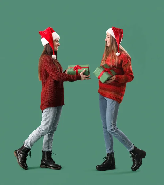 Fiatal Nők Mikulás Kalapok Karácsonyi Ajándékok Zöld Háttér — Stock Fotó