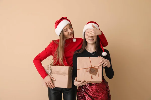 Fiatal Nők Mikulás Kalapok Karácsonyi Ajándékok Bézs Háttér — Stock Fotó