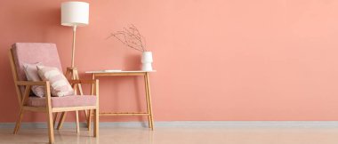 Pembe koltuğu, masası ve lambası olan şık bir oturma odası. Tasarım için pankart