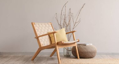 Ahşap koltuklu, puf ve ağaç dallı modern oturma odasının içi.