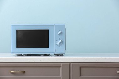 Modern mikrodalga fırın açık mavi duvarın yanında.